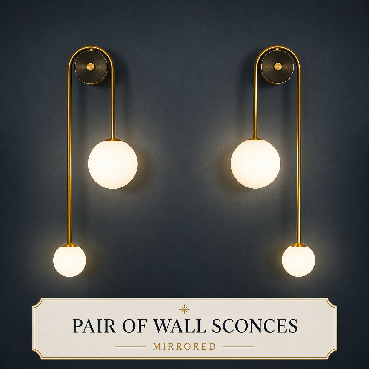 A pair of modern wall sconces with gold-finished metal arms and glowing white spherical glass shades, mounted on a dark navy wall. A cream label at the bottom reads 'PAIR OF WALL SCONCES MIRRORED'.